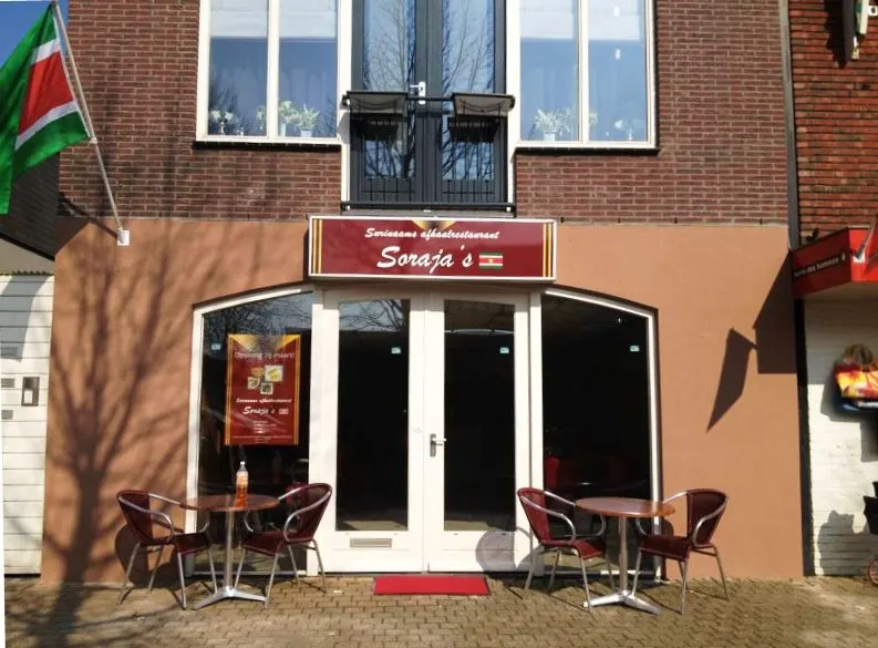 De gevel van Soraja's aan de Gedempte Molenwijk, met terrasstoelen en de Surinaamse vlag